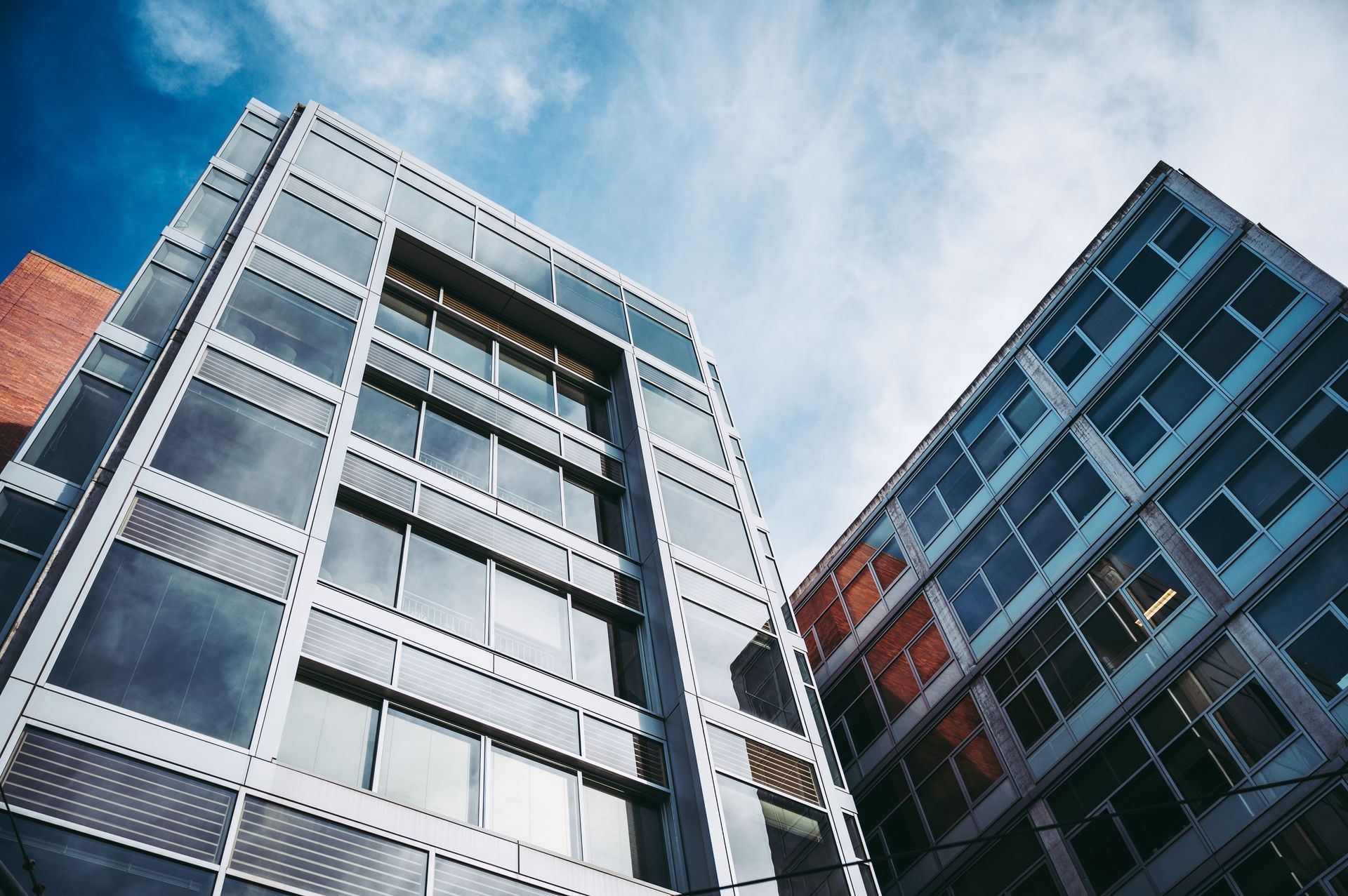 From below of facades of modern buildings in residential district under cloudy blue sky in daytime